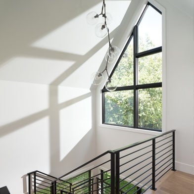 Stairway with high uniquely shaped windows bringing in the natural light