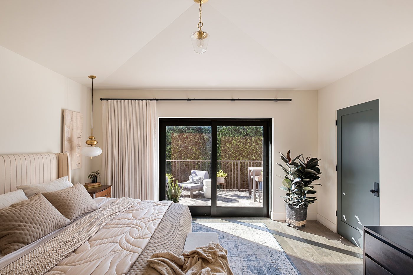 An interior bedroom shot of a black, pocketing MultiGlide Door providing a seamless connection between bedroom and deck.