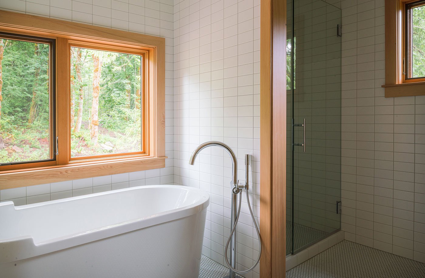 A bathroom with white-tiled walls and Douglas fir E-Series Casement Windows.