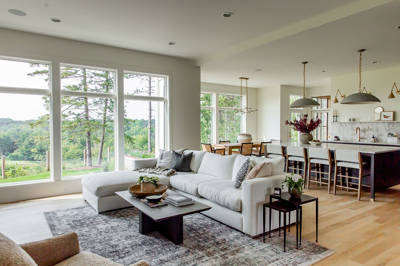 An open-concept living room with large picture windows topped by transom windows.