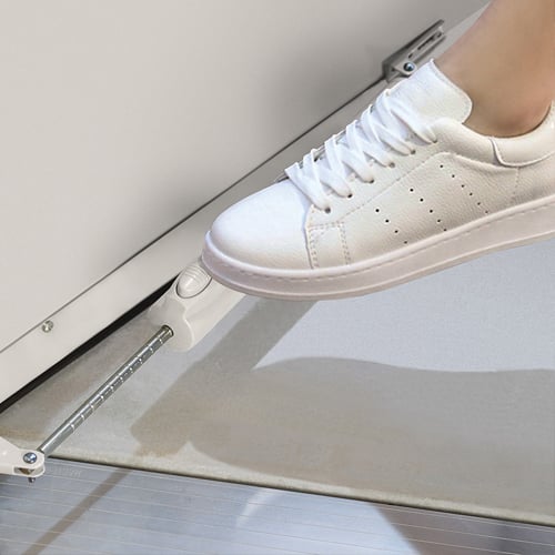 A person keeping a storm door open with a tap of their foot on a Simple Step closer.