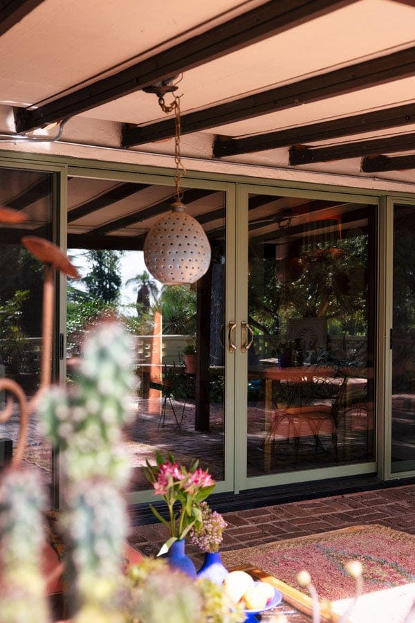 Justina Blakeney poses near her four-panel E-Series Gliding Patio Door with olive exterior, pine interior and a bi-parting opening that makes for a seamless connection between her lanai and courtyard.